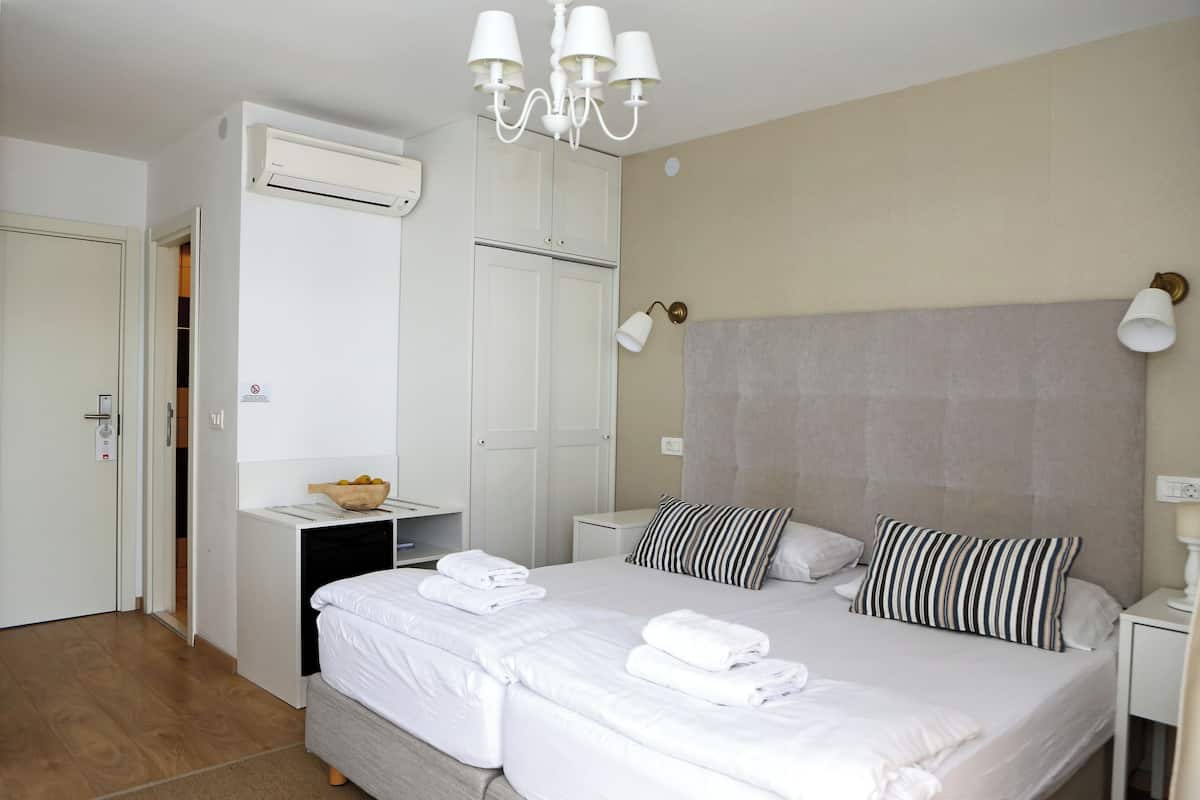 Ein Hotelzimmer mit einem Bett, Nachttischen, einem Kleiderschrank und einer Klimaanlage.