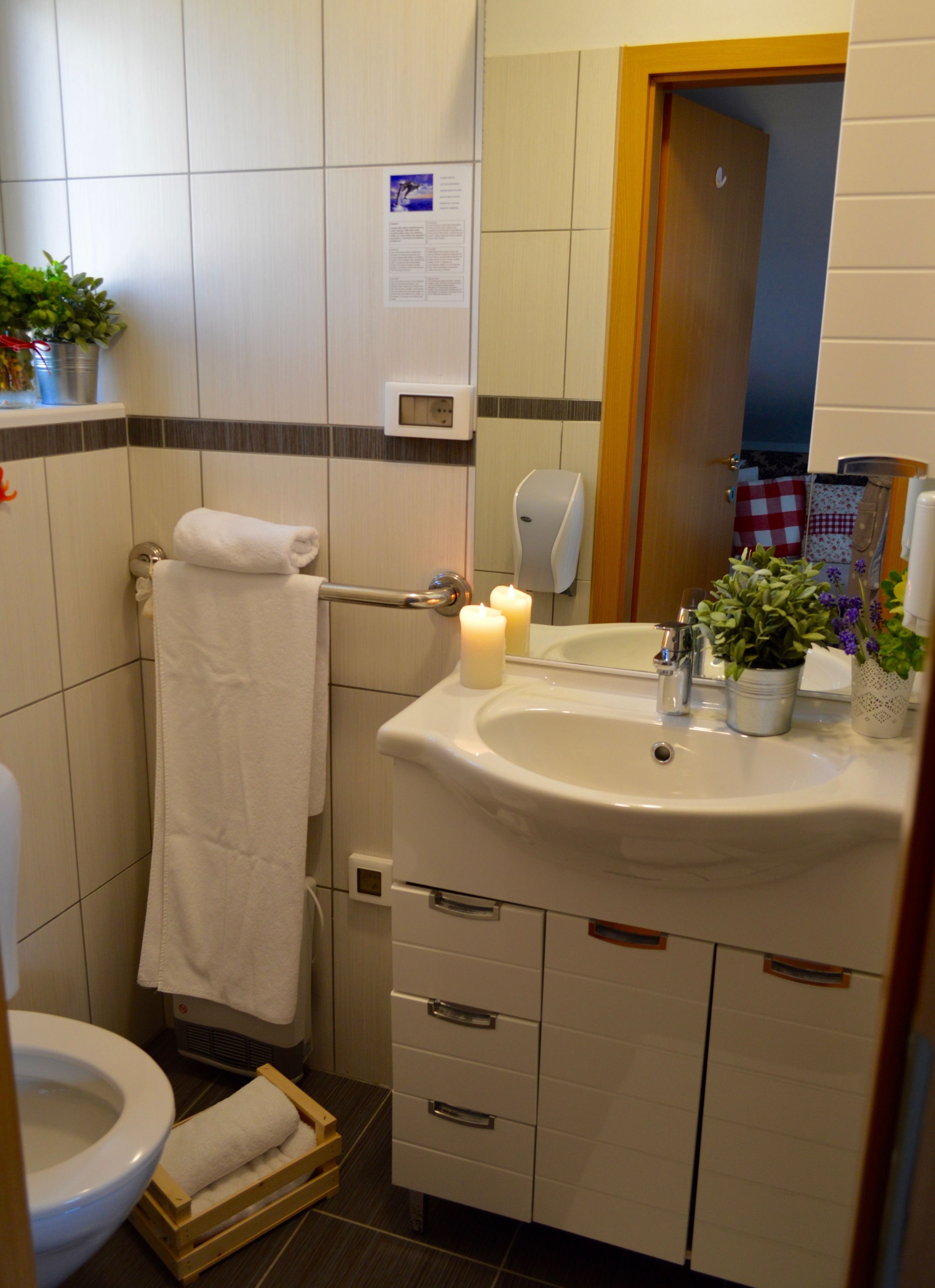A bathroom with a toilet, sink, mirror, towel rack, and a small wooden stool.