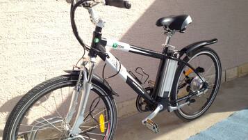 A bicycle parked against a wall with a window in the background.