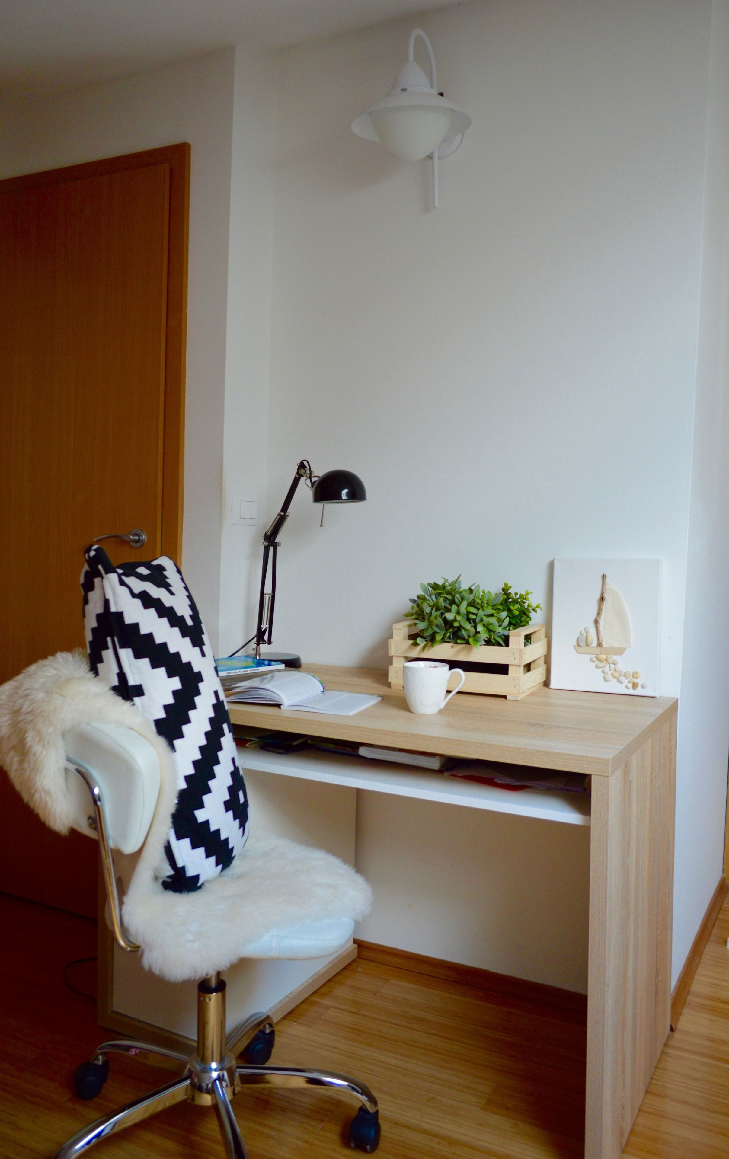 A workspace with a desk, chair, lamp, plant, and decorative items.