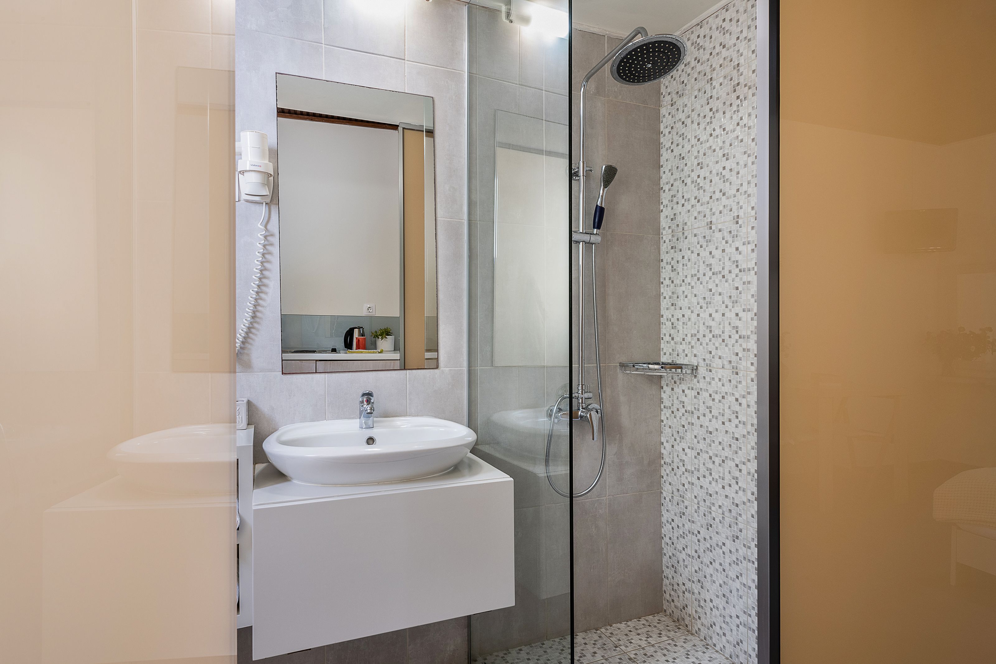 A modern bathroom with a glass-enclosed shower, a white sink, and a mirror above it.