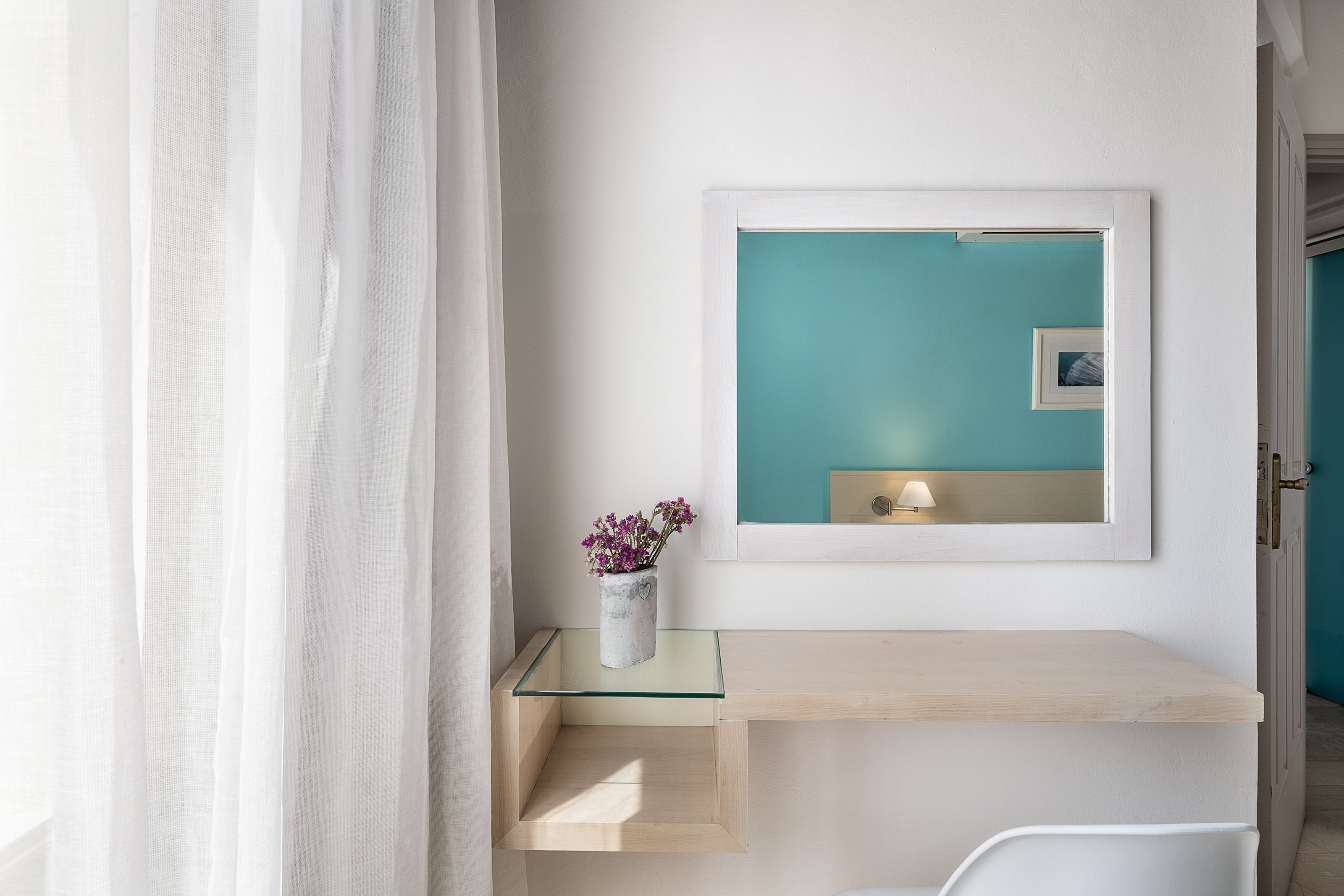 Ein modernes Badezimmer mit einer Glasablage, einem weißen Waschtisch, einer Wand in Türkis und einem gerahmten Bild.