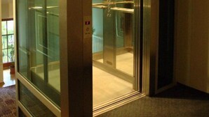Ein Aufzug mit Glasschirmen und Bedienfeld.