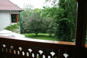 Een balkon met uitzicht op een tuin en een huis.