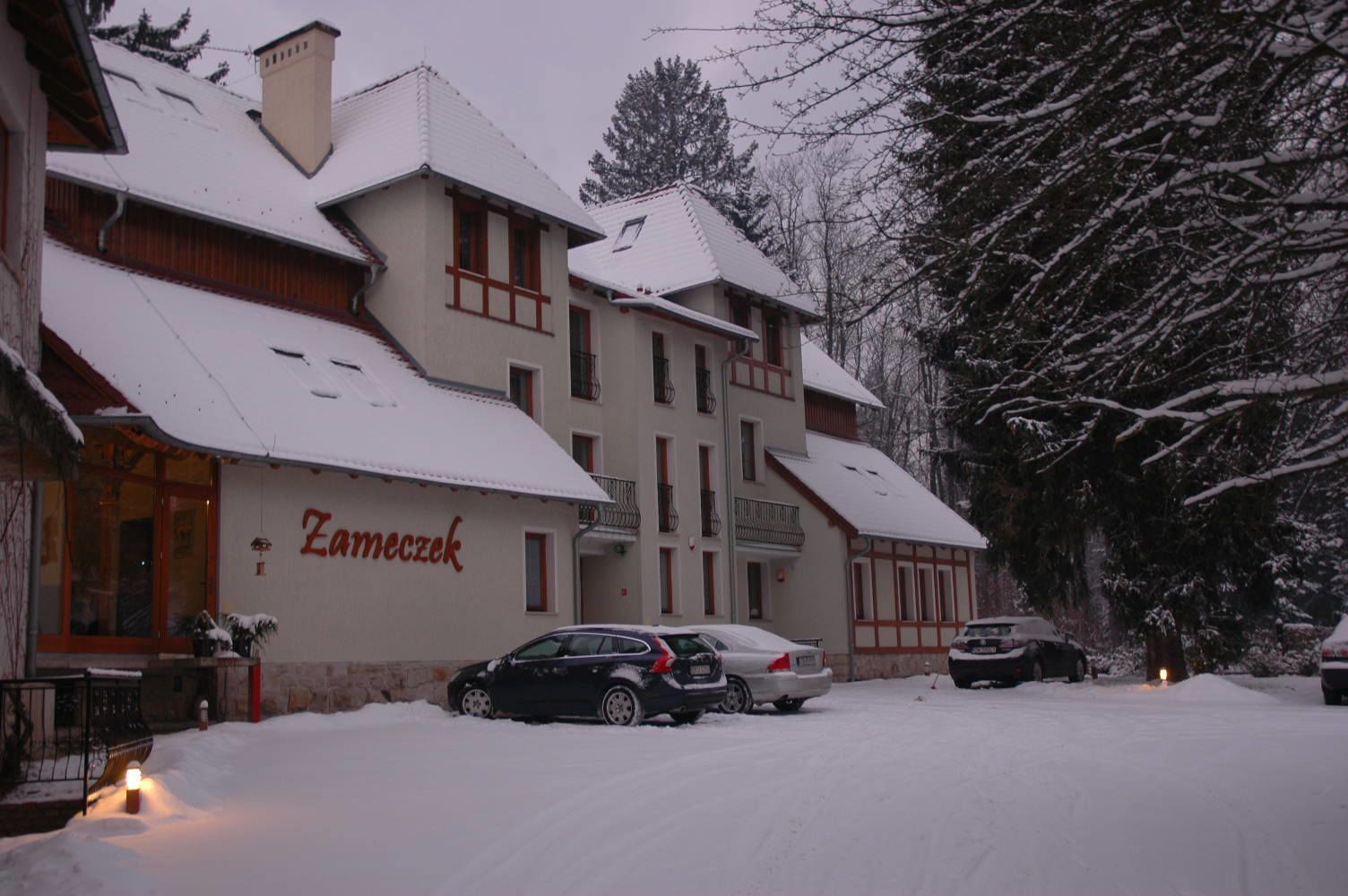 A building with the name 'Zameczek' on the facade, featuring a traditional architectural style with a steeply pitched roof and dormer windows.