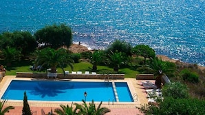 A rectangular pool with a clear blue water surface, surrounded by a paved deck and lush greenery.