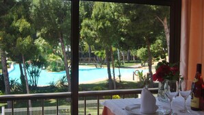 A table set for two with a view of a pool and trees.