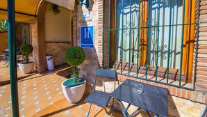 Un patio con piso de baldosas, una mesa, sillas, una planta en maceta y un cartel que indica un hotel.