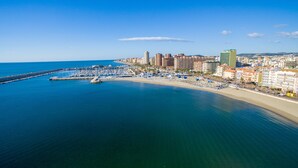 Un paisaje urbano costero con un puerto deportivo, una playa y edificios altos.