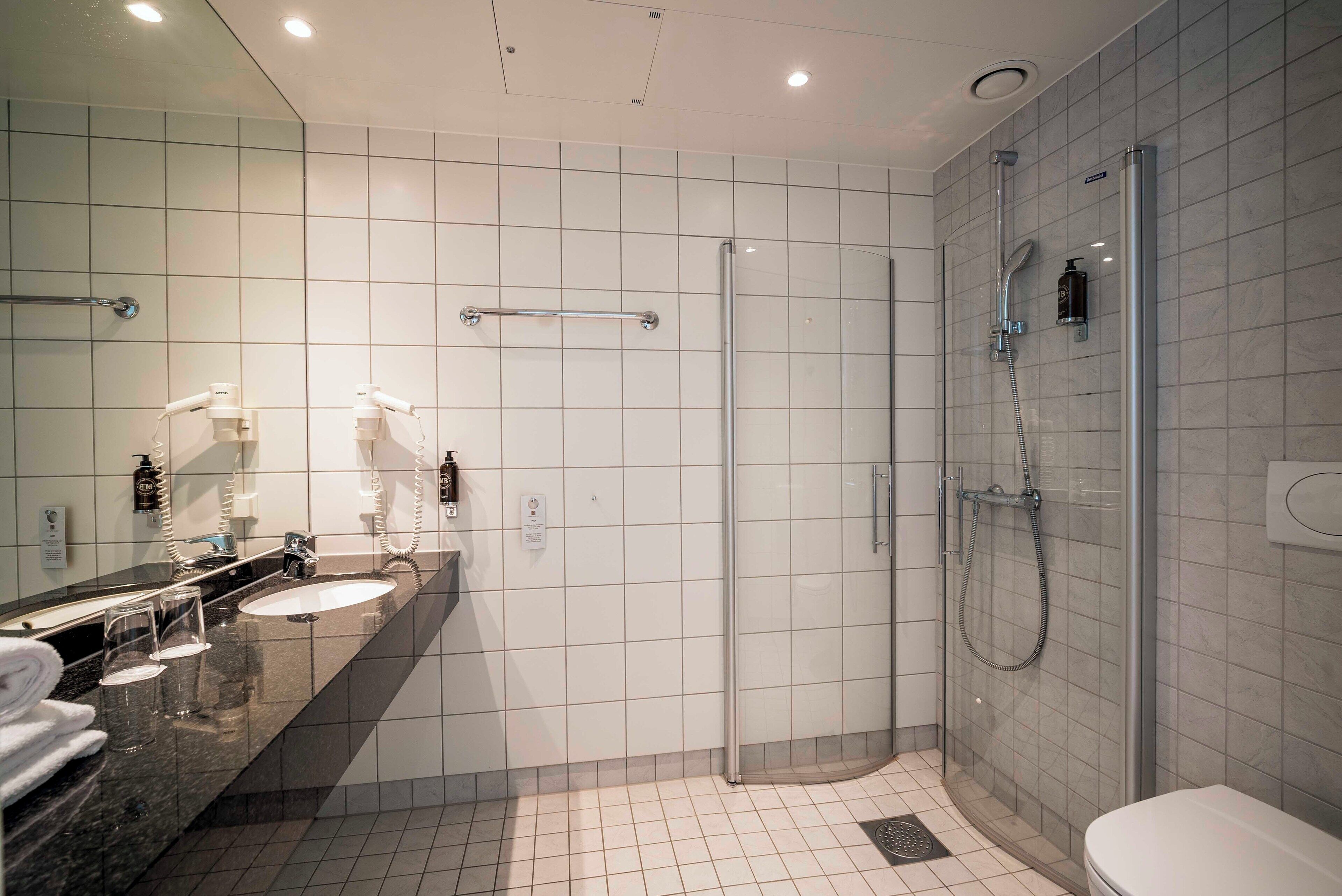 A modern bathroom with a glass-enclosed shower, a vanity with a mirror, and a toilet.