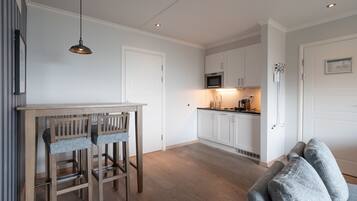 Una cocina moderna con armarios blancos, una mesa de comedor de madera y un microondas empotrado.