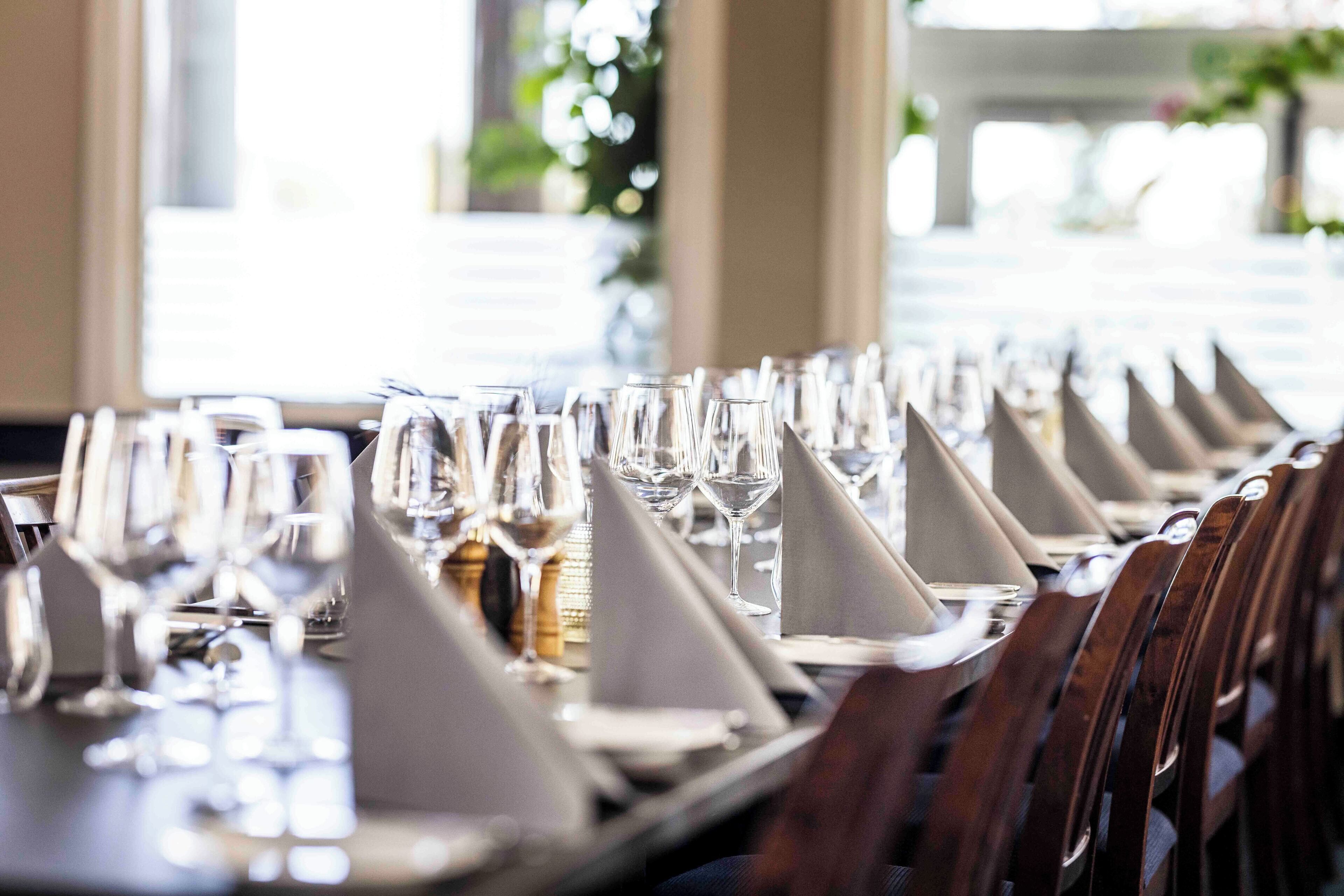 A dining table set with multiple wine glasses, napkins, and cutlery, indicating a formal dining arrangement.