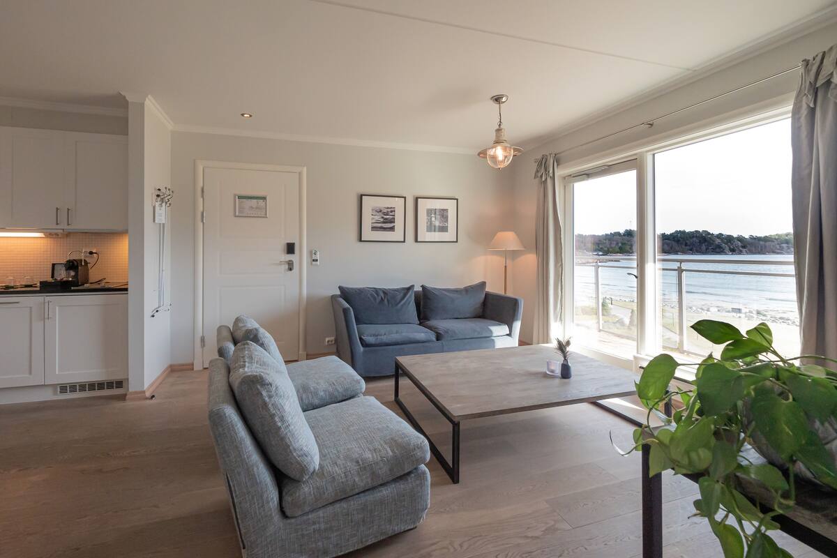 Un salón moderno con un sofá gris, una mesa de centro y vistas al mar.