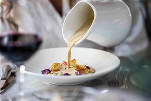 Un plato blanco con salsa cremosa que se vierte desde una jarra blanca.