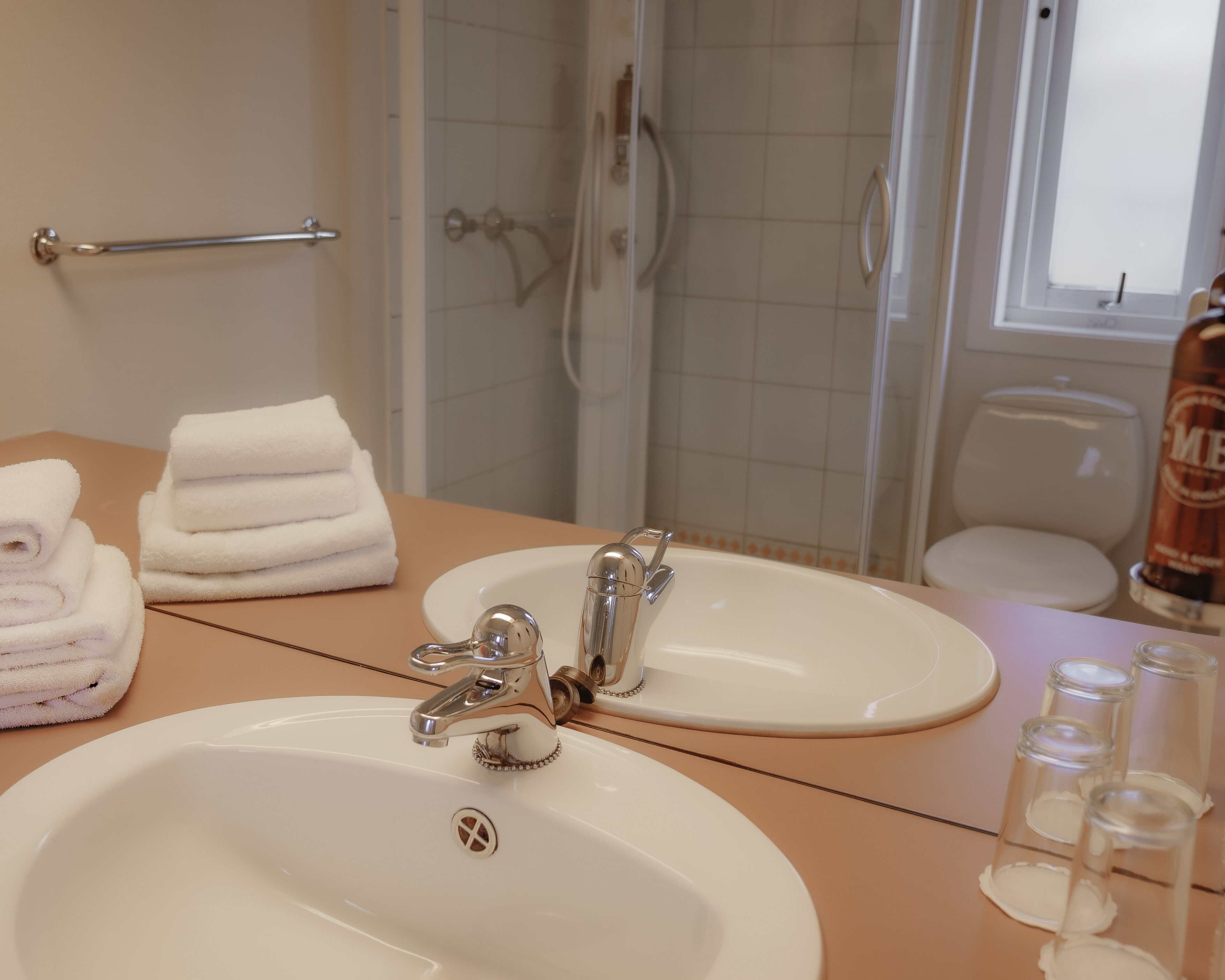 A bathroom with a sink, two mirrors, a towel rack, and a shower area.
