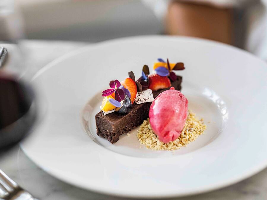 A dessert plate with a chocolate brownie, fruit, and ice cream.