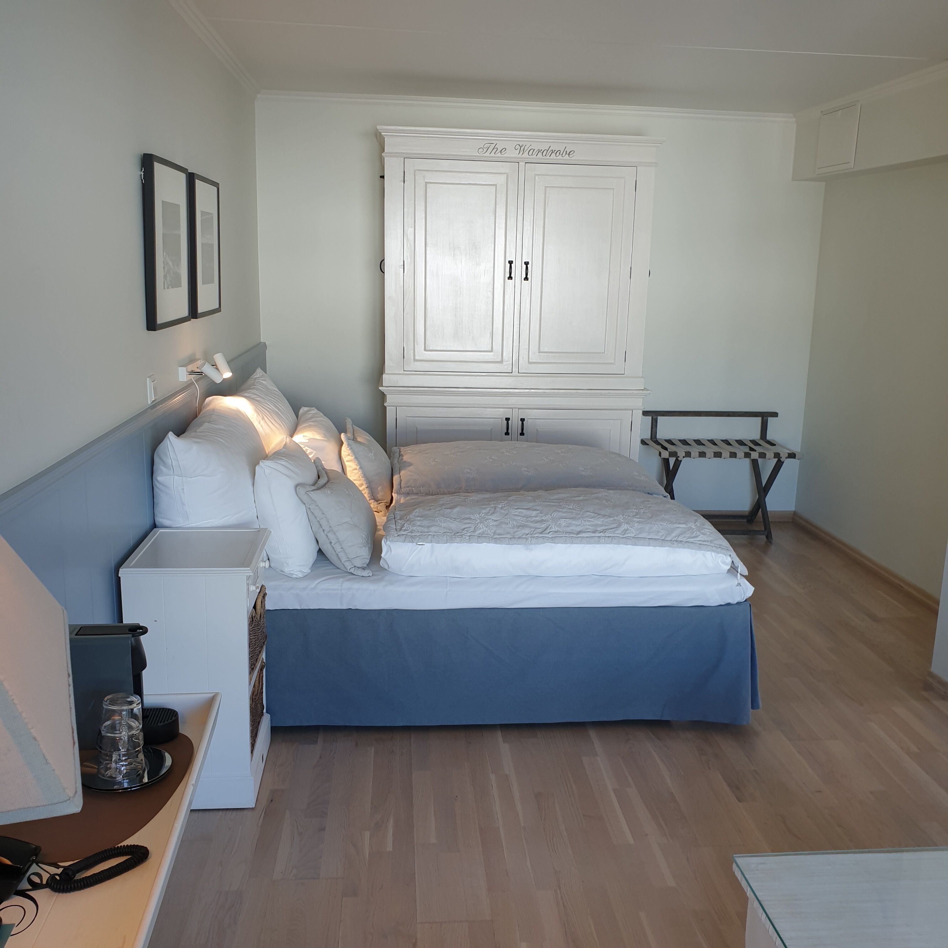 Une chambre à coucher comprenant un lit, des tables de chevet, une armoire et un petit banc.