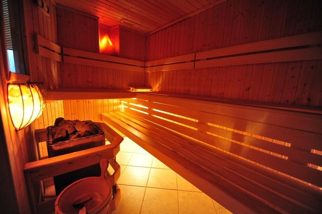 A sauna with wooden benches and a bench with a bucket.