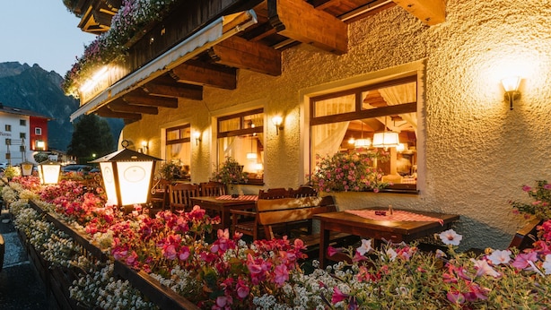 A restaurant with outdoor seating, wooden beams, and flower arrangements. - Hotel Post Fusch (Fusch an der Grossglocknerstrasse)