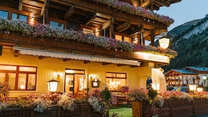 A hotel with a restaurant, wooden balconies, and flower boxes. - Hotel Post Fusch (Fusch an der Grossglocknerstrasse)