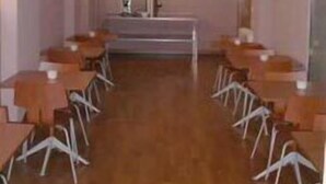 Una sala de conferencias con una larga mesa y sillas, un atril y un extintor en la pared.