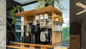 A coffee station with a tea box, coffee makers, and jars of sugar and coffee.