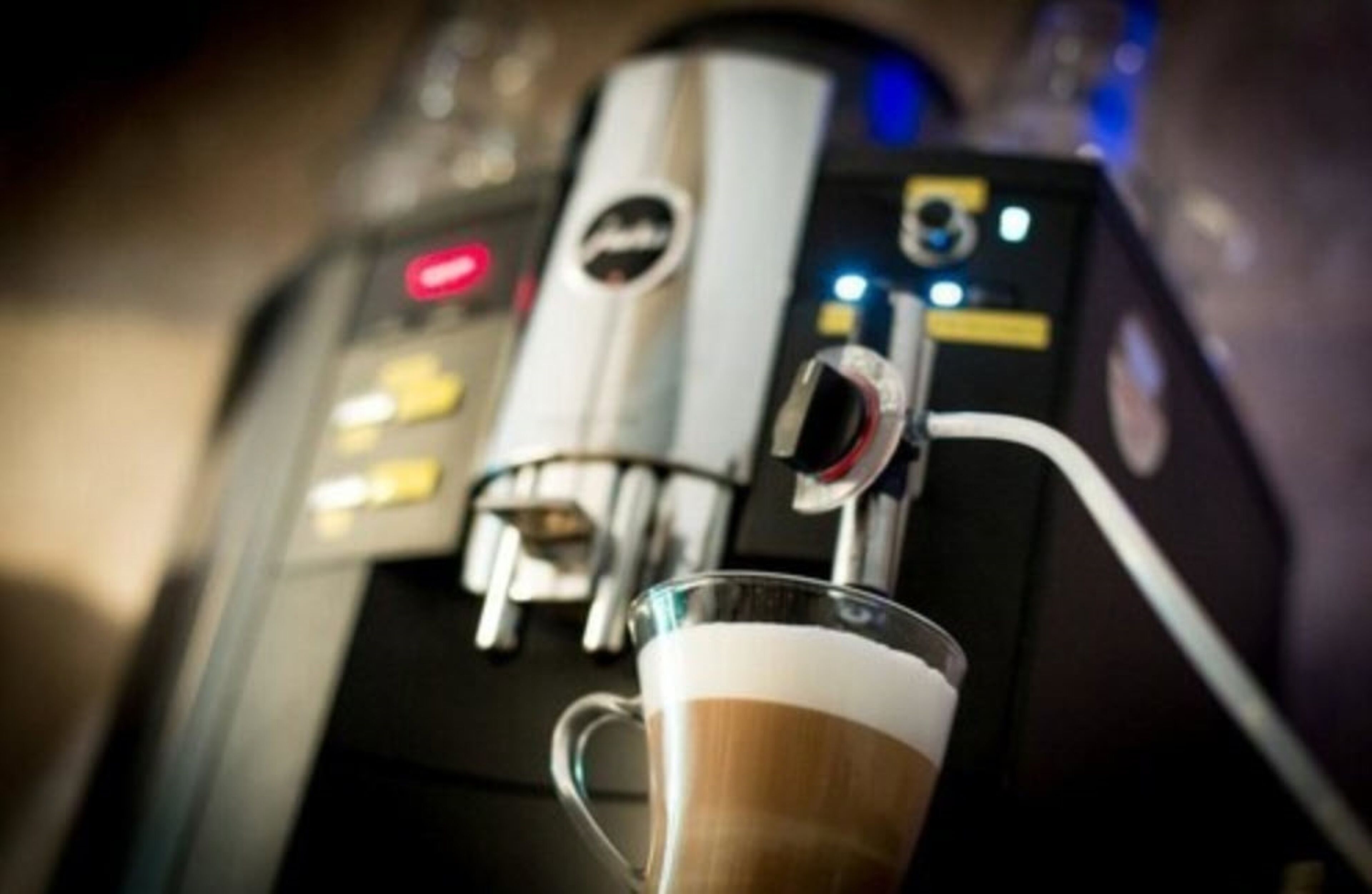 A close-up of a coffee machine with a glass cup of coffee.