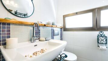 A bathroom with a white sink, a mirror, a toilet, and a window.