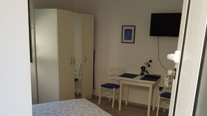 A bedroom with a bed, a desk, a chair, a wardrobe, and a TV mounted on the wall. - Stipan Studio & Room (Split)