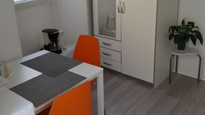 A small, modern room with a white desk, orange chair, and a wardrobe. - Stipan Studio & Room (Split)