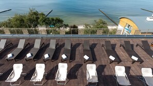 Een loungehoek aan het strand met ligbedden en parasols, met uitzicht op de zee.
