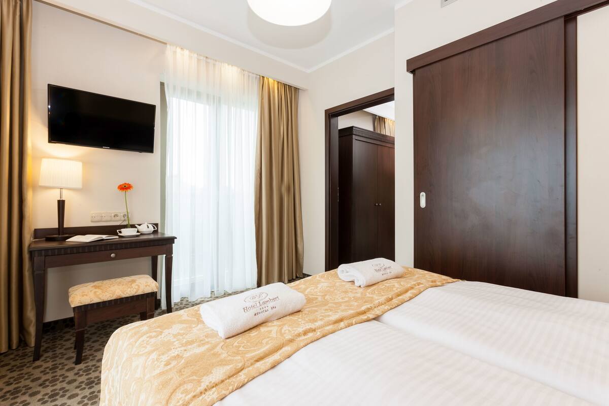 Una habitación de hotel con cama, escritorio, televisor y puerta.