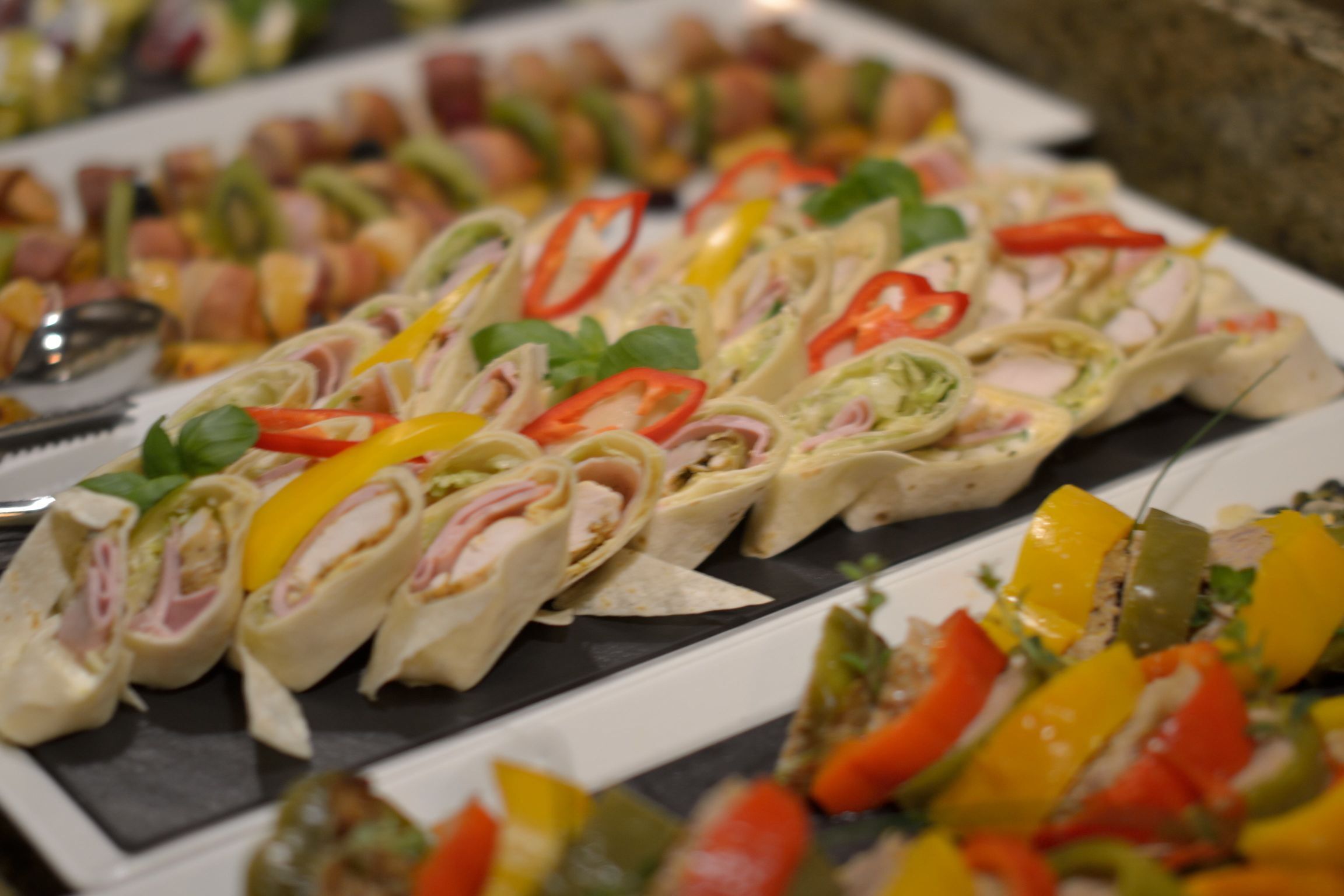 Un tavolo del buffet con diversi cibi, tra cui panini e spiedini di verdure.
