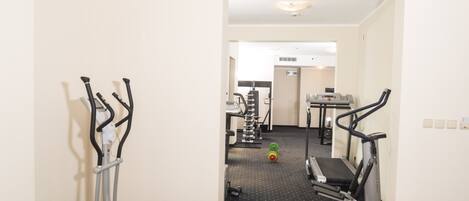Ein Fitnessraum mit Laufbändern, einem Crosstrainer und einem roten Trainingsball.