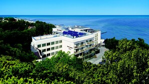 Een hotel met een terras op het dak, zonnepanelen en uitzicht op de oceaan.