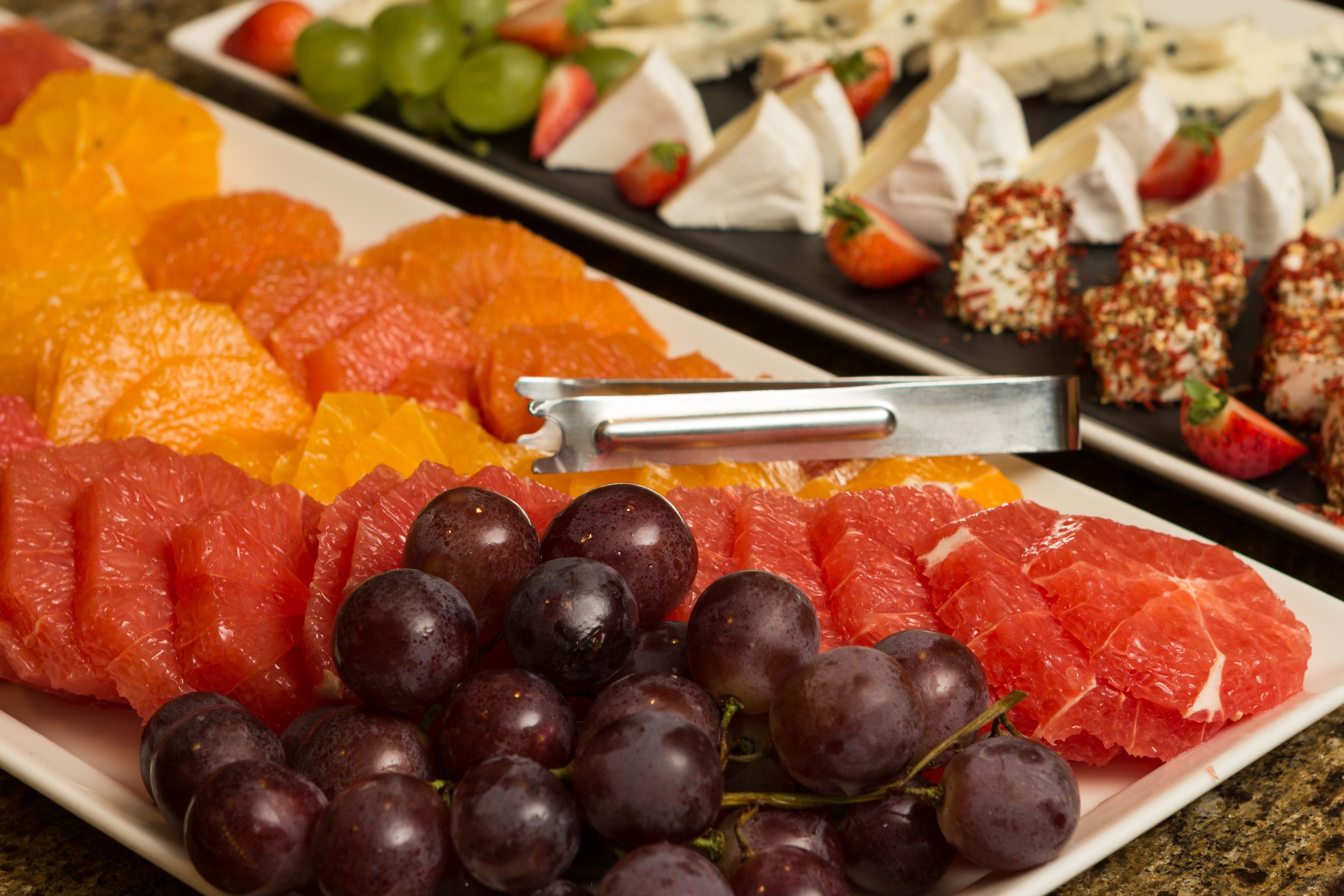 Una selección de frutas frescas y quesos sobre una bandeja.