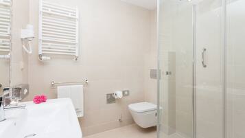 Un baño moderno con cabina de ducha de vidrio, un lavamanos blanco y un inodoro.
