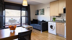 Un espacio habitable funcional con comedor, sofá, lavadora y kitchenette.