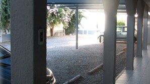 A covered outdoor area with a gravel path, a parked car, and a vehicle in the background. - Tunkelén Apart Hotel (Mendoza)
