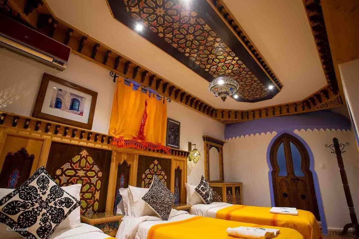 A traditional room with two beds, ornate ceiling, and decorative wall panels.