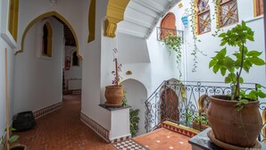 Un pasillo con arcos, plantas en macetas y suelo a cuadros.