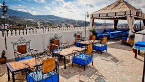 Terraza en la azotea con mobiliario exterior, una zona cubierta y vistas panorámicas de un valle.