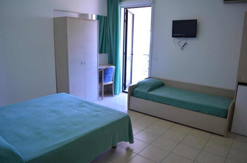 A room with two beds, a TV, a chair, and a wardrobe.