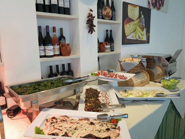 Montaje de bufé con diferentes alimentos y botellas de vino.