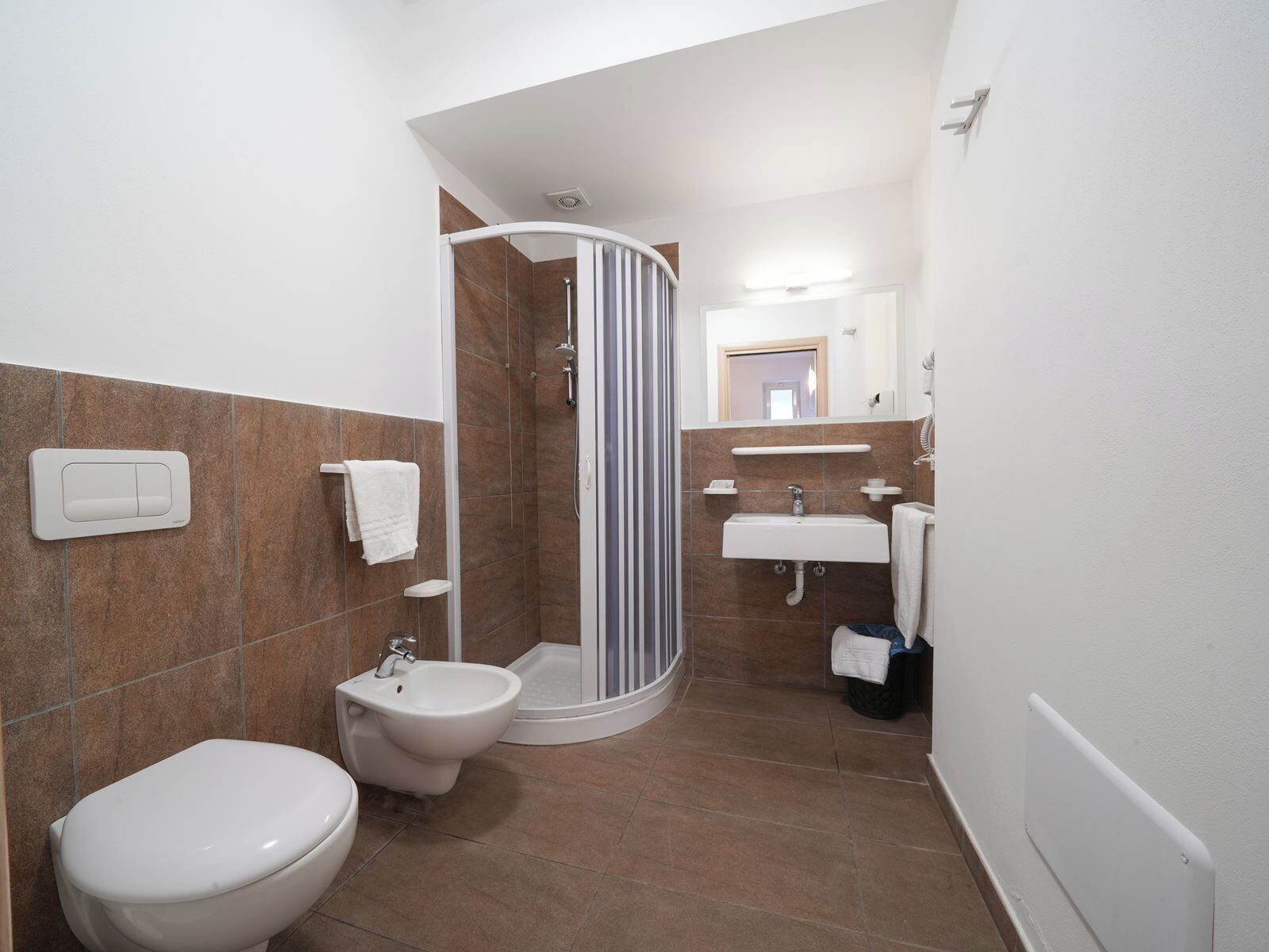 Une salle de bain moderne équipée de toilettes, d’un bidet, d’une douche et d’un lavabo.