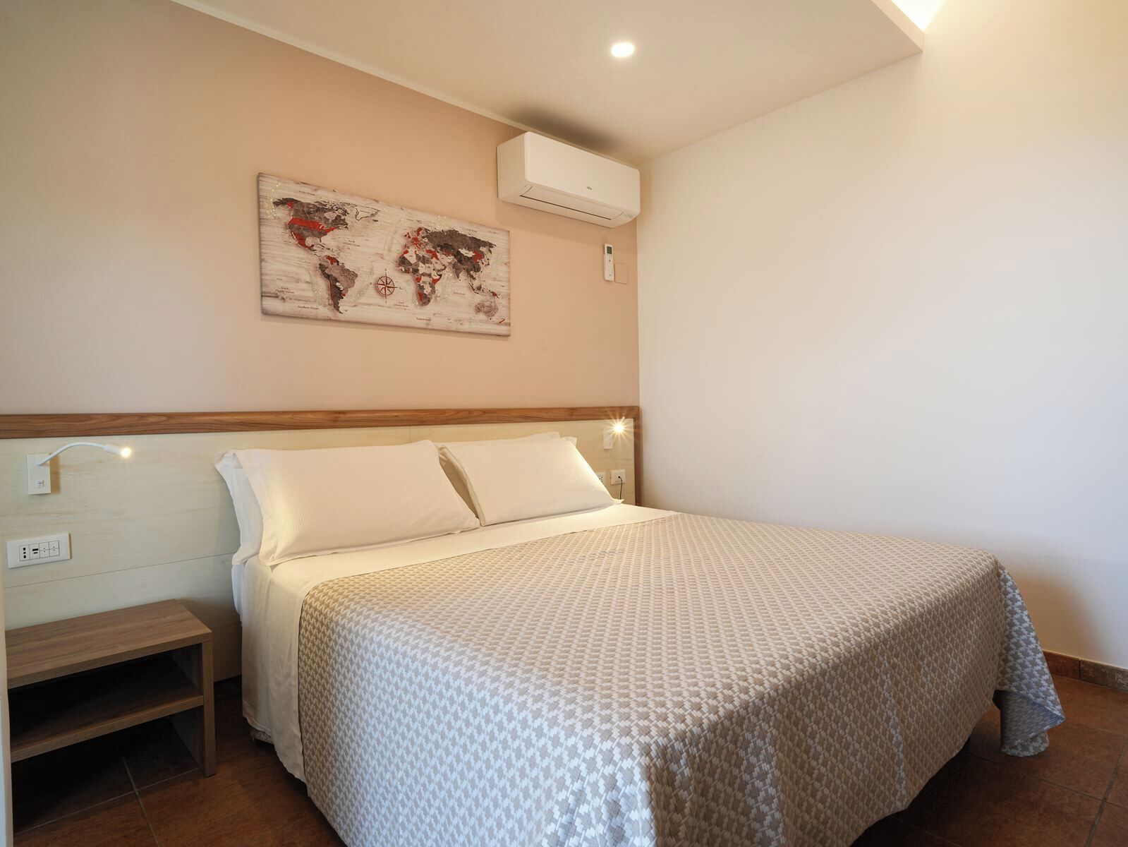 A neatly arranged bedroom with a bed, bedside tables, and a world map artwork on the wall.