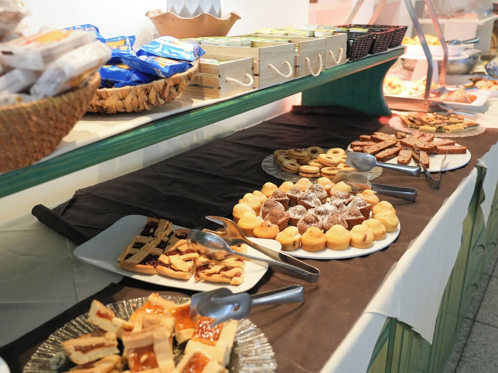 A buffet with various food items including pastries, sandwiches, and desserts.