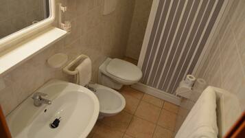 Une salle de bain équipée d’un lavabo, de deux toilettes, d’une douche et d’un porte-serviettes.