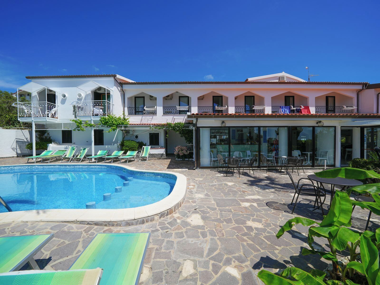 Ein Hotel mit Swimmingpool, Außenbereich zum Sitzen und einem zweistöckigen Gebäude mit Balkonen.