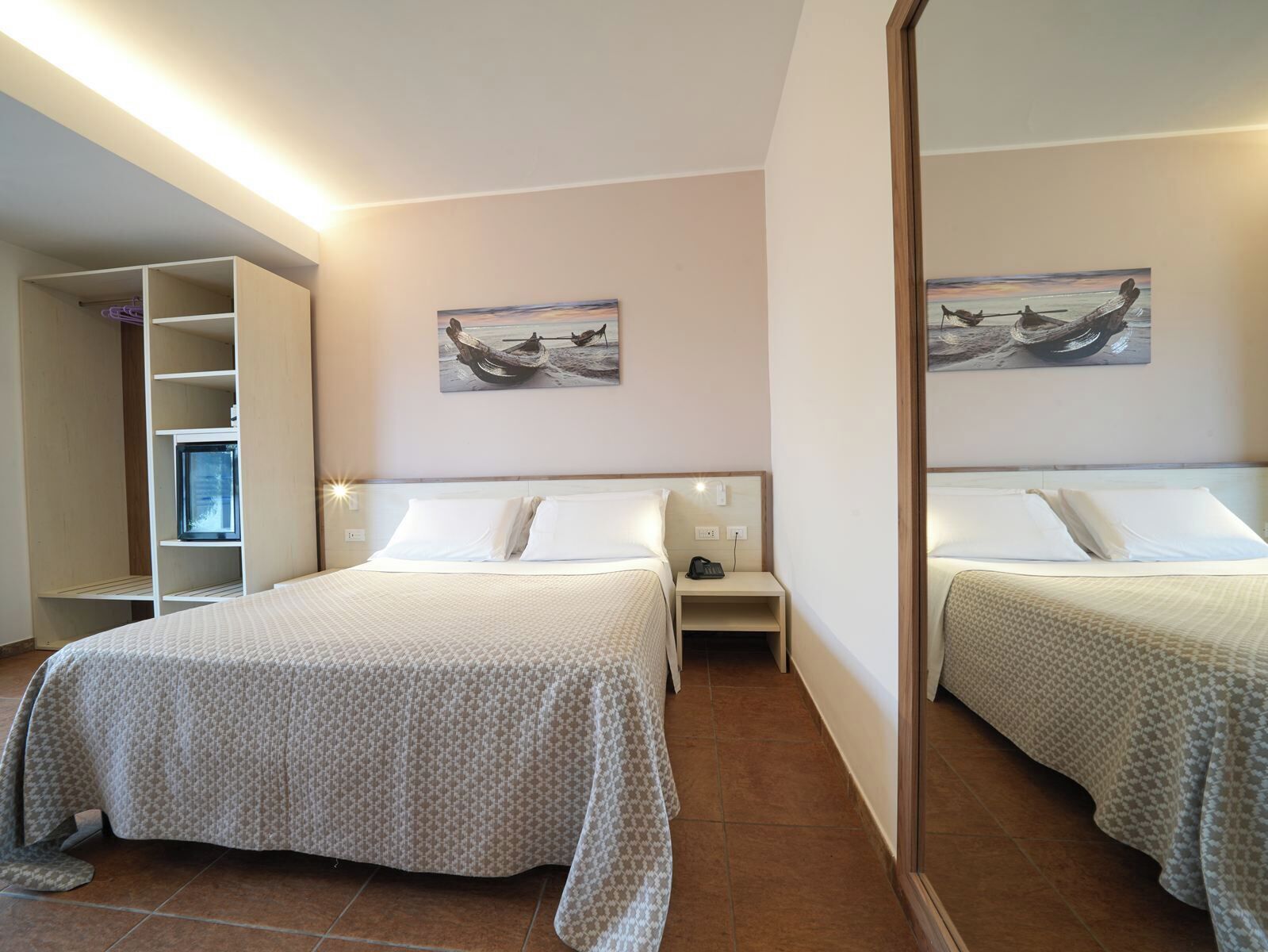 A bedroom with two beds, a wardrobe, a painting on the wall, and a mirror.